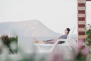 Una persona relajándose en una silla reclinable blanca con vistas a la montaña.