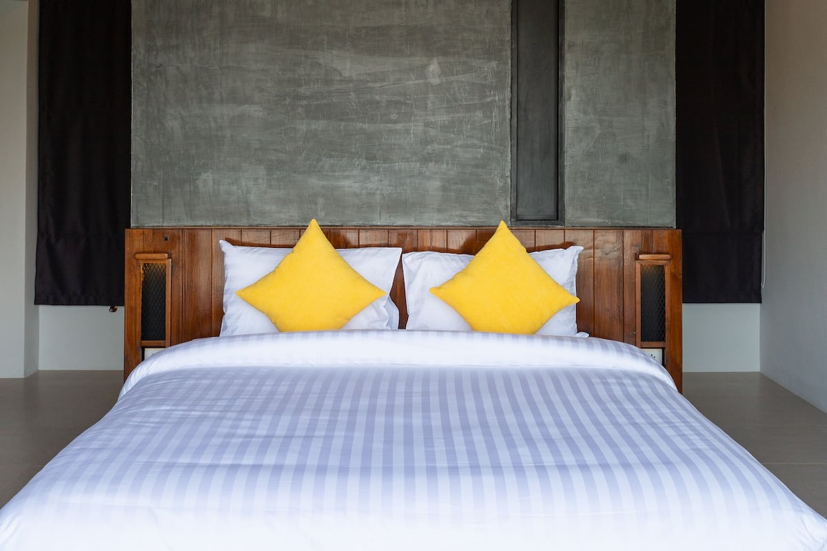 A large bed with a wooden headboard, white bedding, and two yellow pillows.