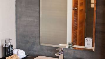 A bathroom with a white sink, a mirror, and a wooden cabinet.