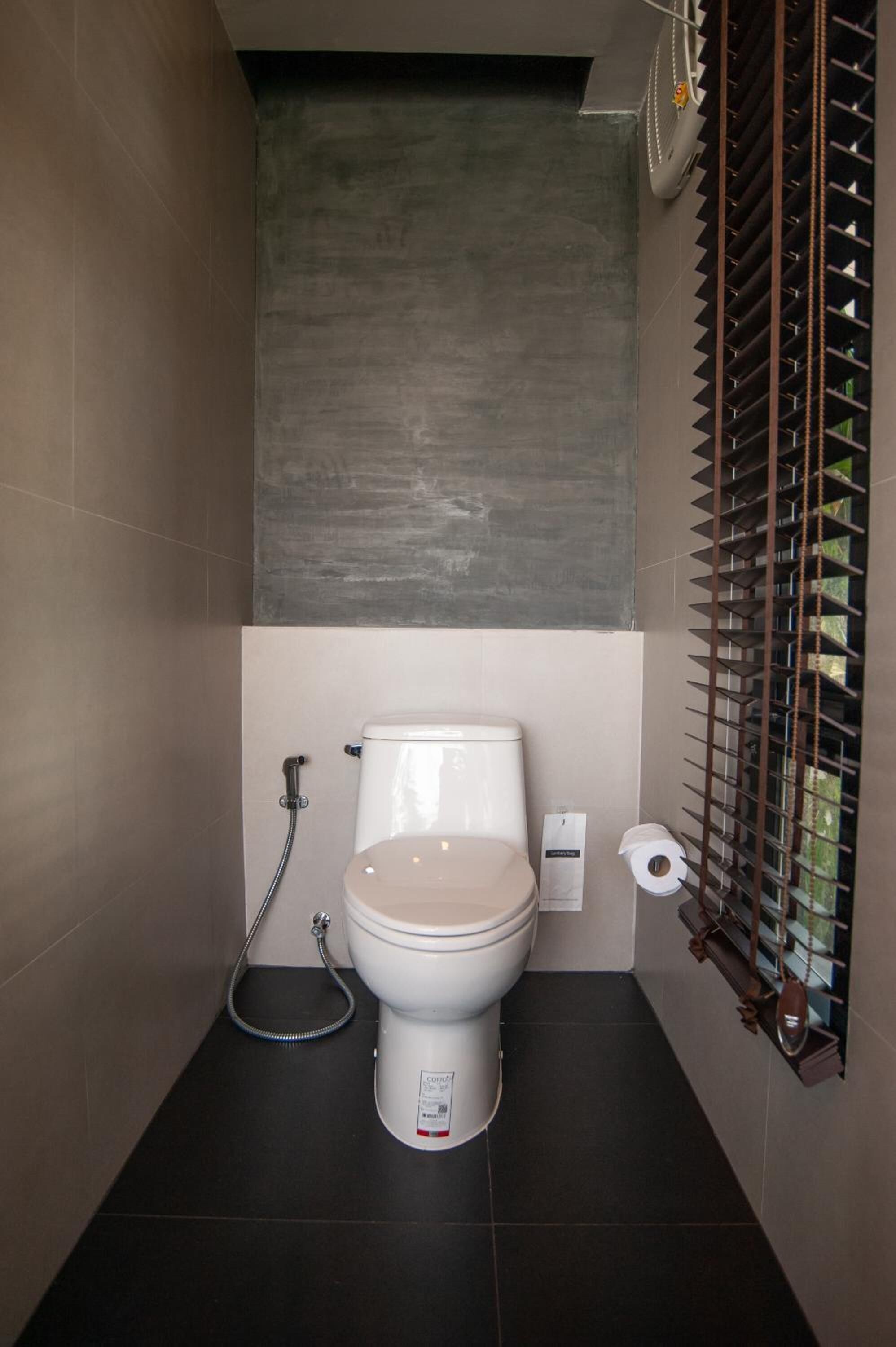 A compact bathroom with a toilet, a shower, and a toilet paper holder.
