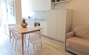 Eine moderne Küche mit weißen Schränken, einem Holztisch und einem beigen Sofa.