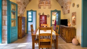 Un coin repas avec une table et des chaises en bois, un réfrigérateur rouge et un téléviseur posé sur un meuble en bois.