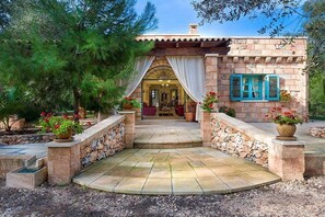 A stone building with a tiled entrance, potted plants, and a view into the interior.