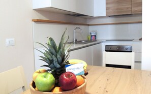 Eine Küche mit Holztisch, Obstschale, Spüle und Schränken.
