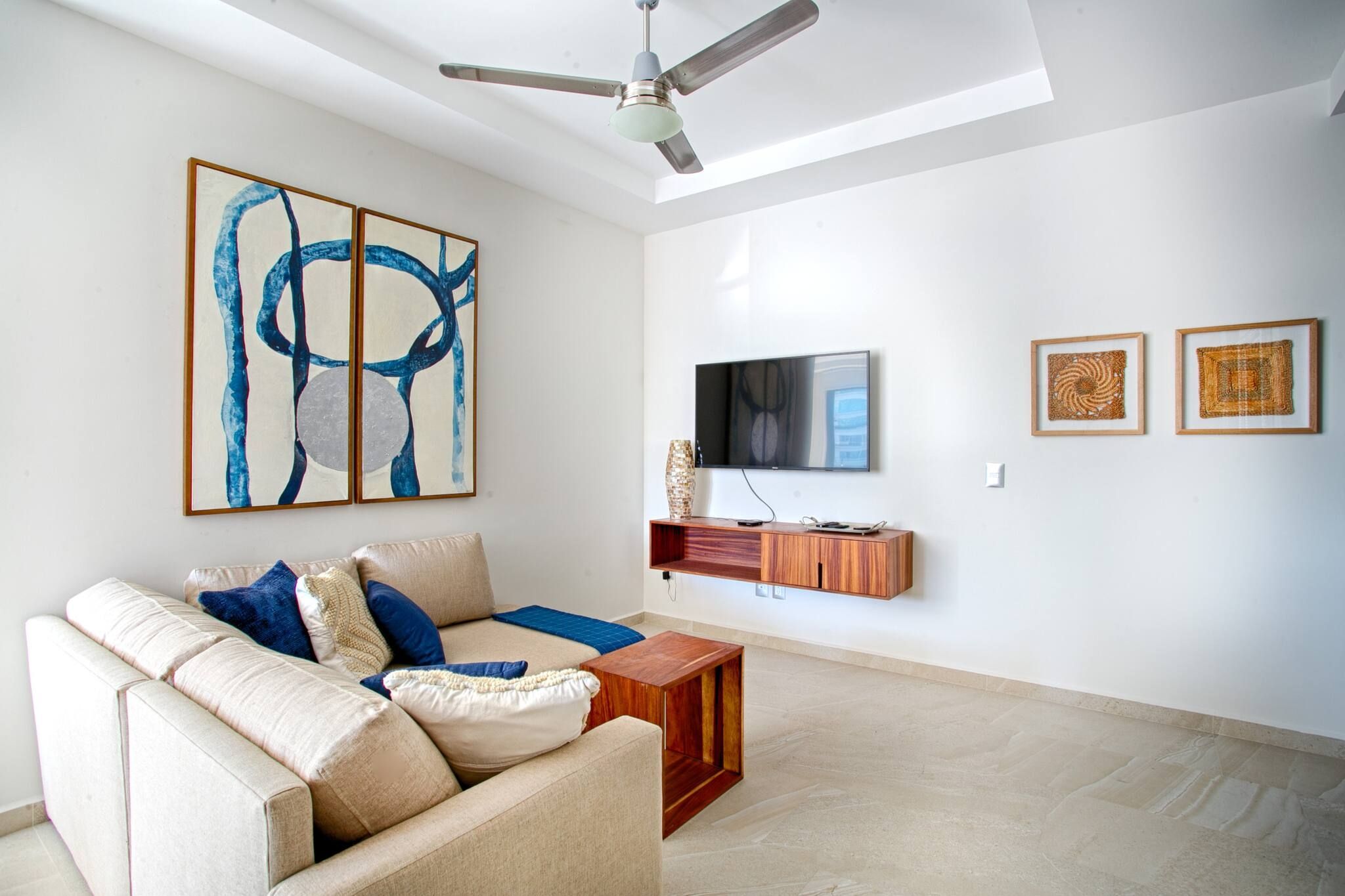A modern living room with a beige sofa, a wooden coffee table, and abstract art on the wall.