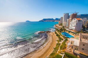 Un paisaje urbano costero con playa, edificios altos y cielo despejado.