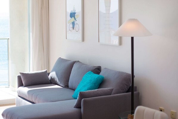 Un salon moderne avec un canapé gris, un coussin turquoise et une lampe sur pied.