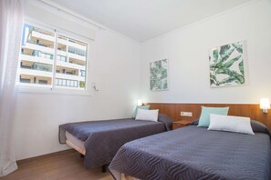 Quarto de hotel com duas camas, janela e vista para um prédio.
