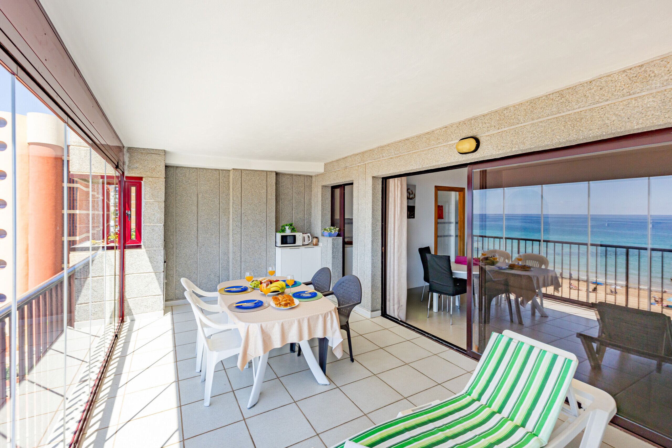 Ein Balkon mit Esstisch, Stühlen und einer Liege.