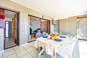 A dining area with a table set for two, a kitchen in the background, and a sliding glass door leading to another room. - Apartment Calpeplaya - PlusHolidays (Calpe)