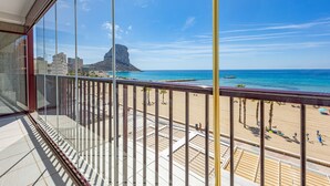 Ein Balkon mit Blick auf einen Strand, Palmen und ein Berg in der Ferne.
