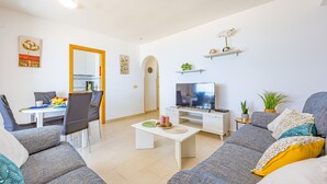 Ein modernes Wohnzimmer mit Essbereich, Fernseher und Sofa.