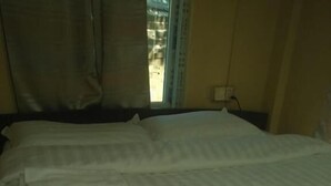 A bed with a striped bedspread and a pillow. - My Family - Hostel (Nyaung-U)
