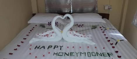 Una cama con una decoración en forma de corazón y la frase 'HAPPY HONEYMOONER' bordada en la colcha.