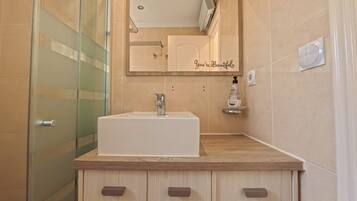 A modern bathroom with a white sink, wooden vanity, and a mirror with a motivational quote.