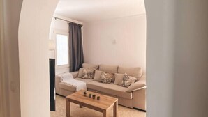 Un salon avec un canapé, une table basse et une fenêtre avec des rideaux.