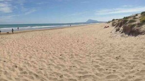 Une vaste plage de sable fin, avec des vagues douces et un ciel dégagé.