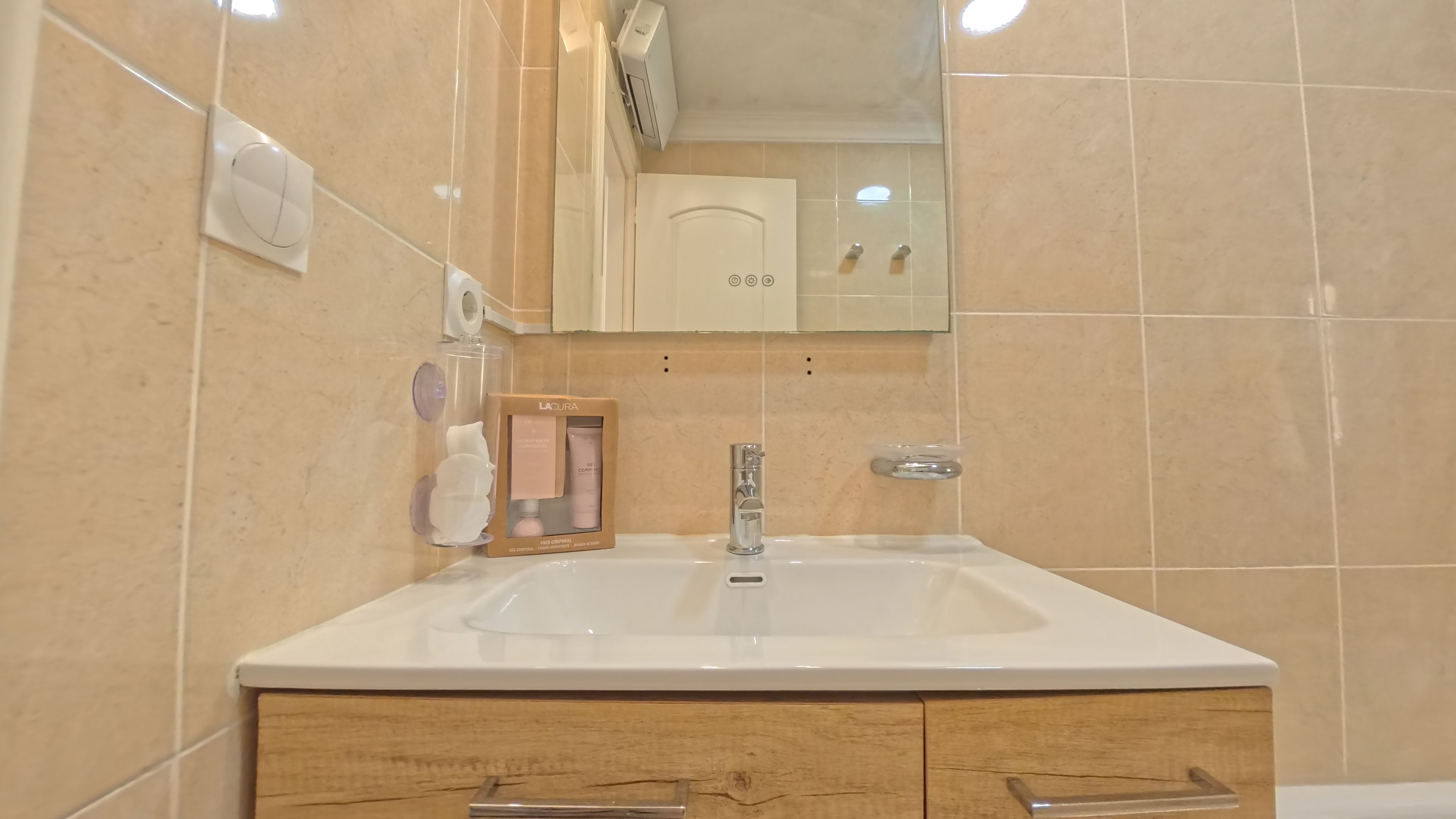 A bathroom with a white sink, a mirror, and a wooden cabinet with drawers.