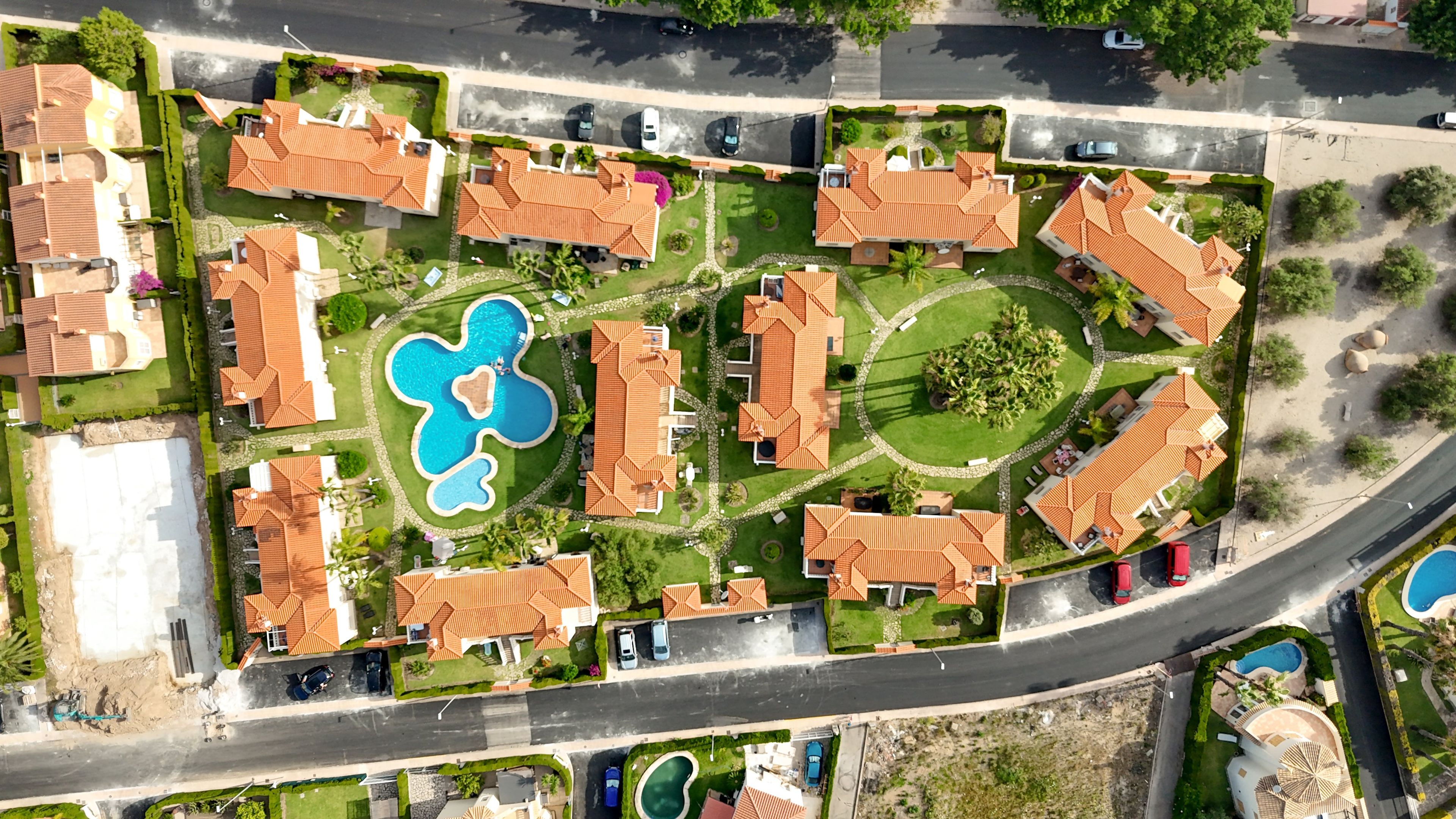 Vista aérea de una zona residencial con varias casas, una piscina y una carretera.
