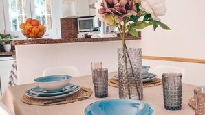 Une table à manger dressée avec de l’assiette bleue, un vase rempli de fleurs et un saladier d’oranges.