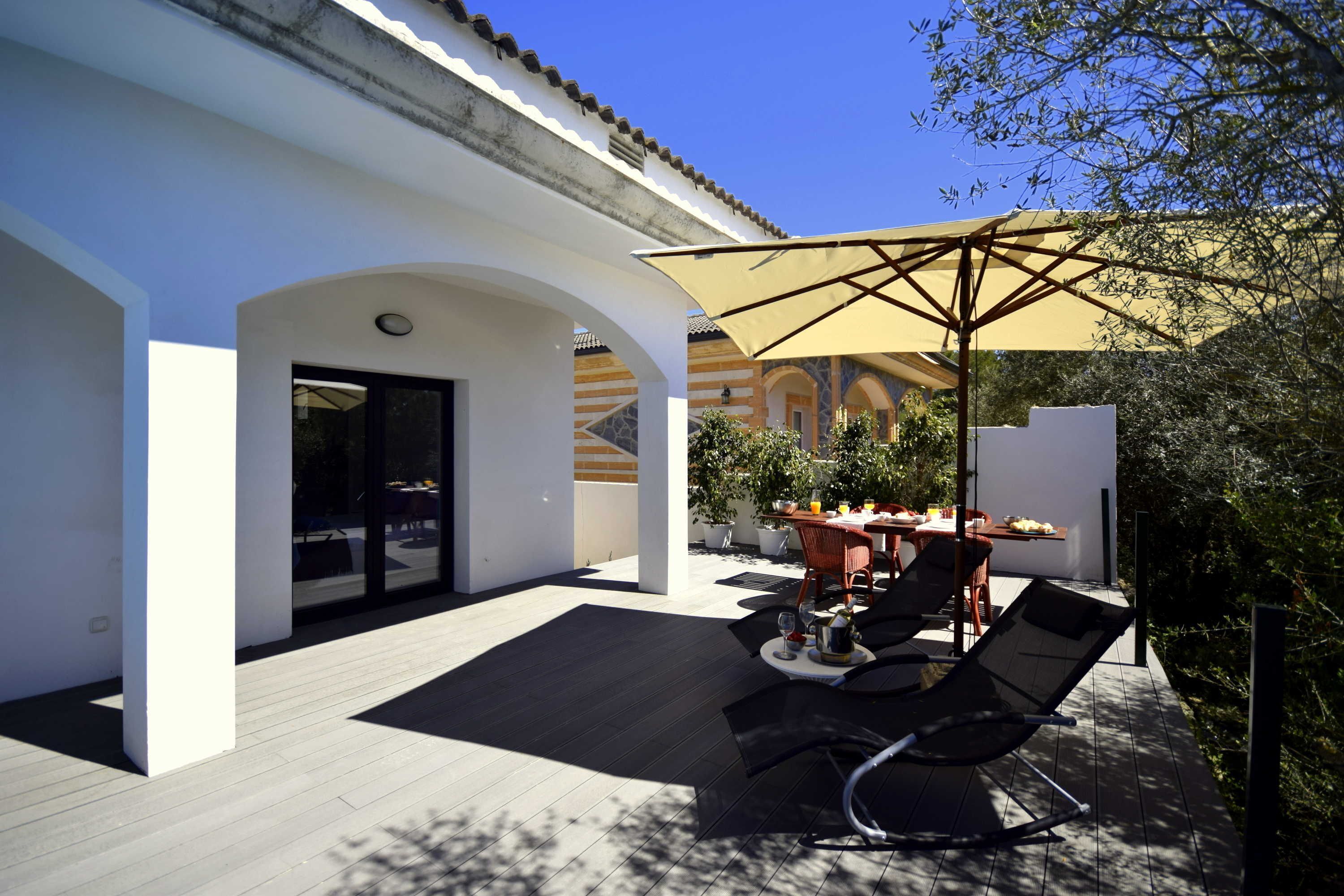 A patio area with a table and chairs, a large umbrella, and a view of a building with arches.