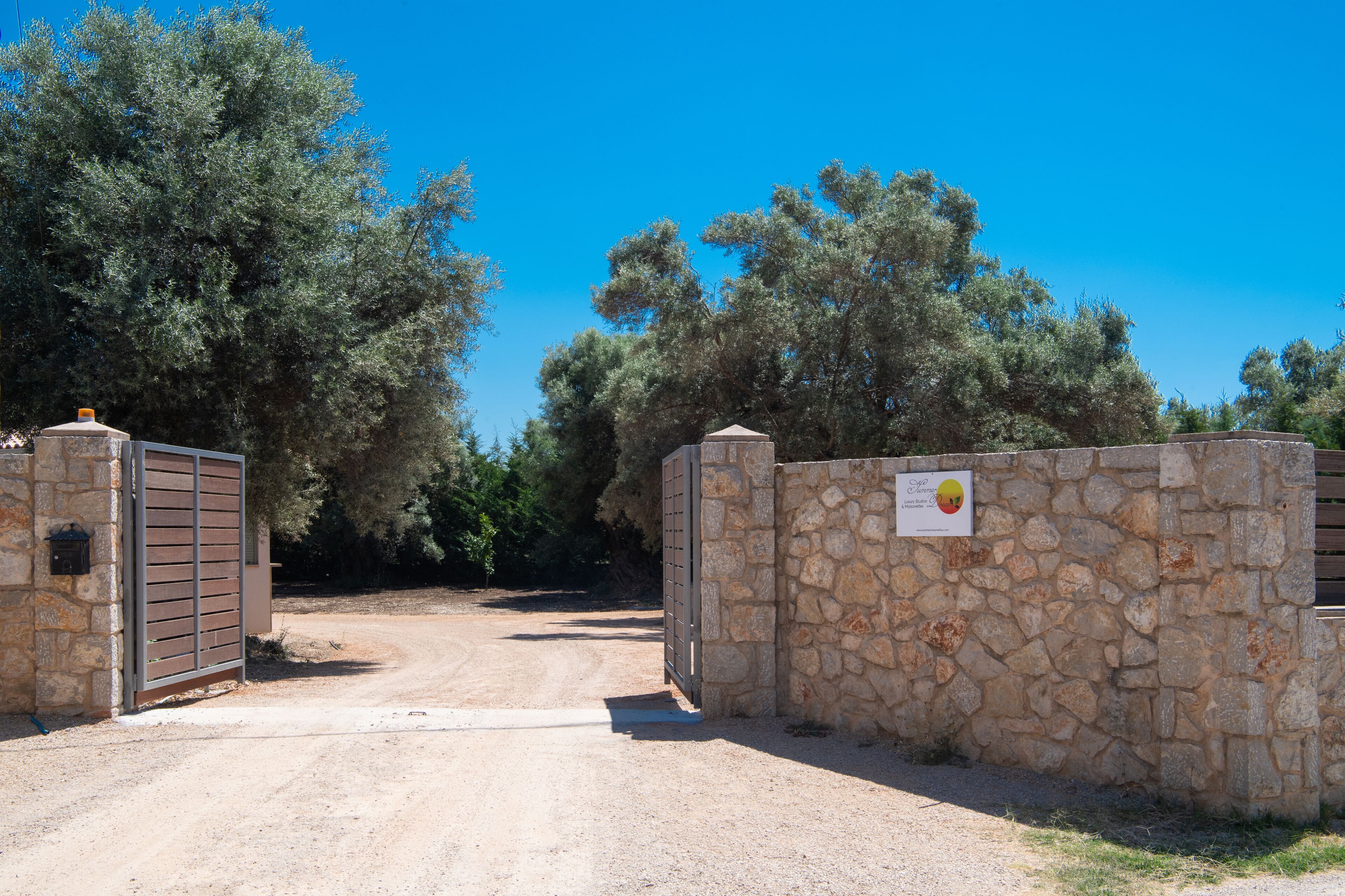 Una entrada protegida per murs de pedra i un senyal, envoltada d'arbres.