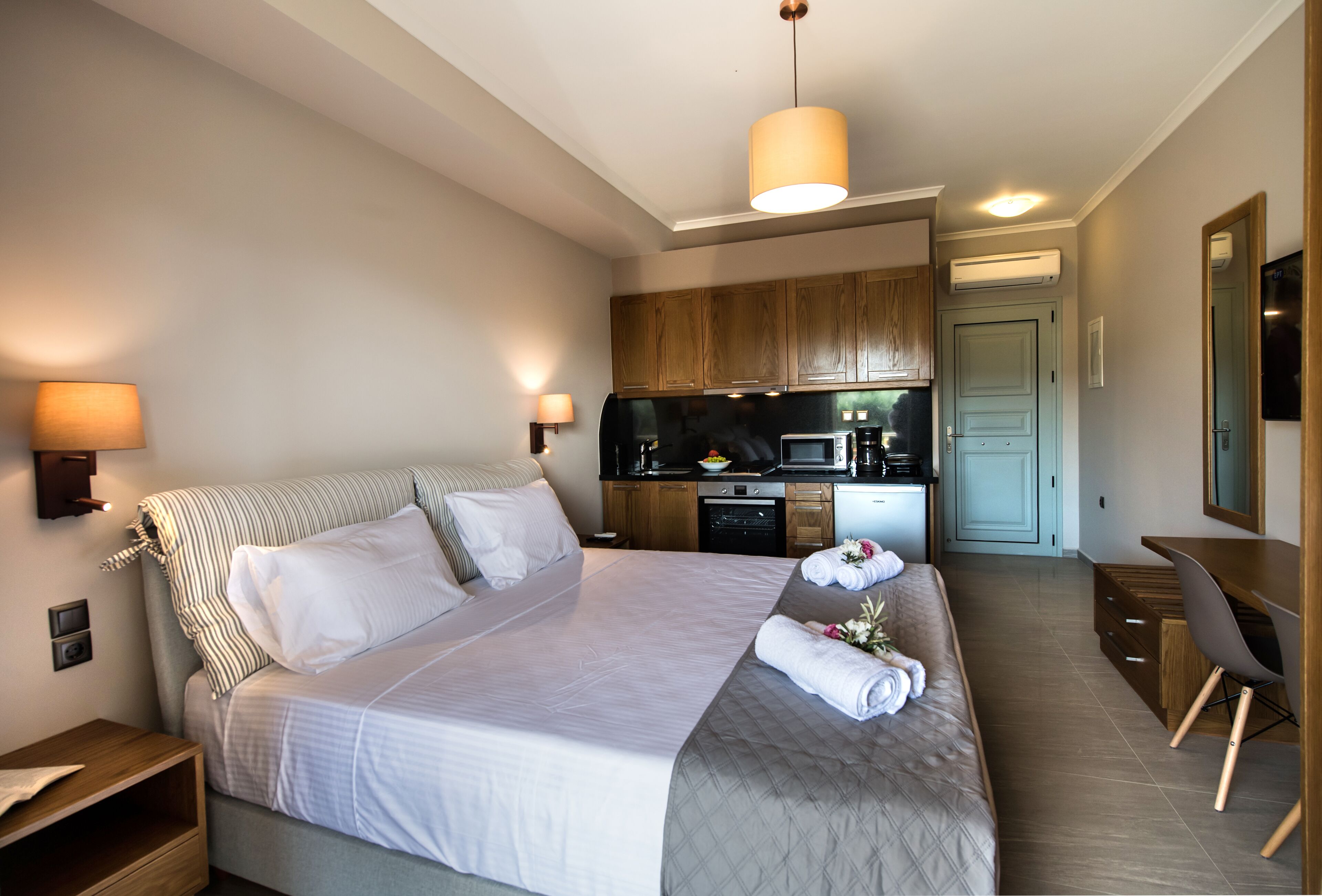 Una habitación de hotel con una cama grande, un escritorio, kitchenette y un baño.