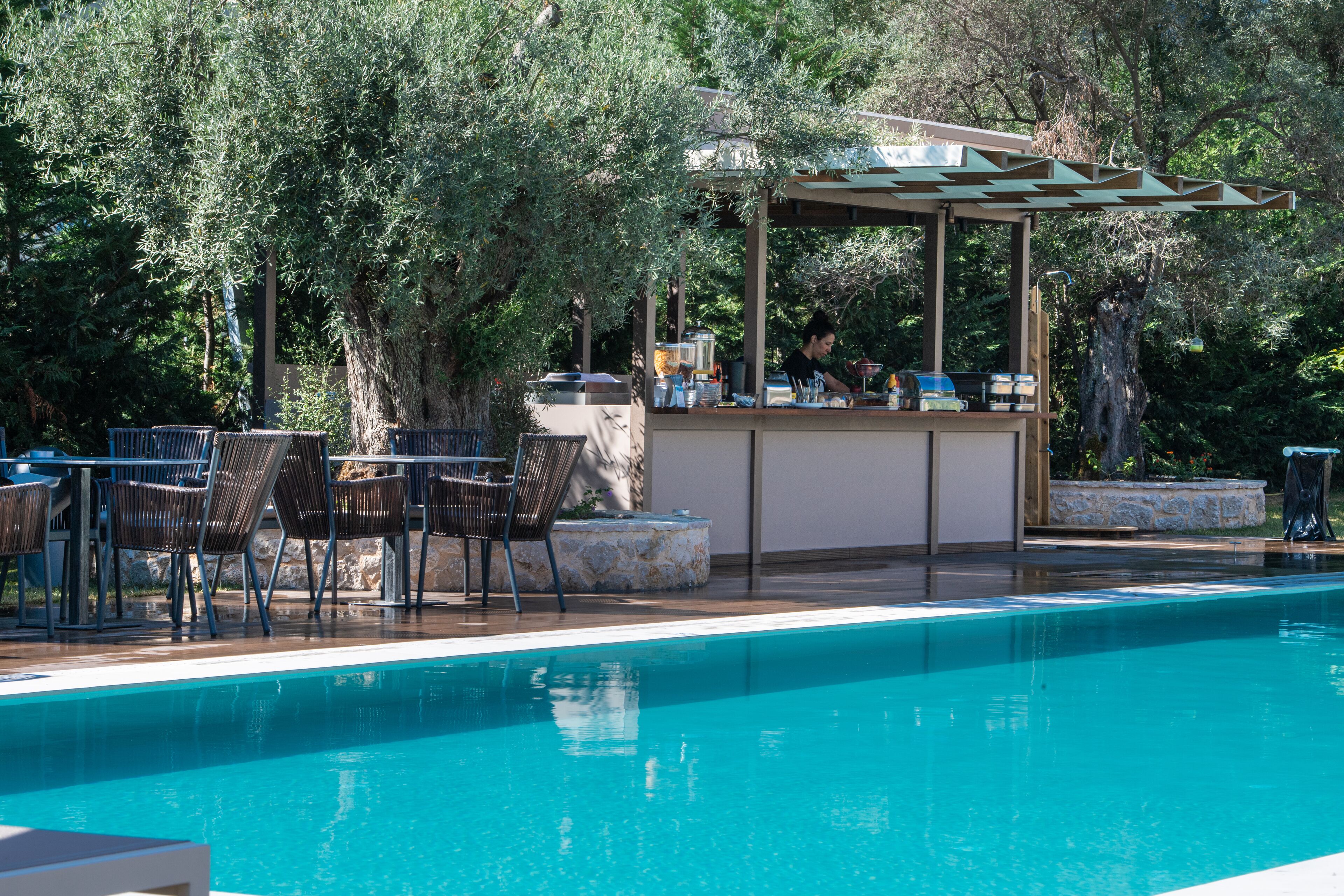A poolside area with a bar, lounge chairs, and a pergola.