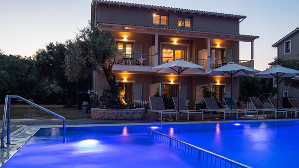 Um edifício de dois andares com piscina, área de estar ao ar livre e varanda bem iluminada.