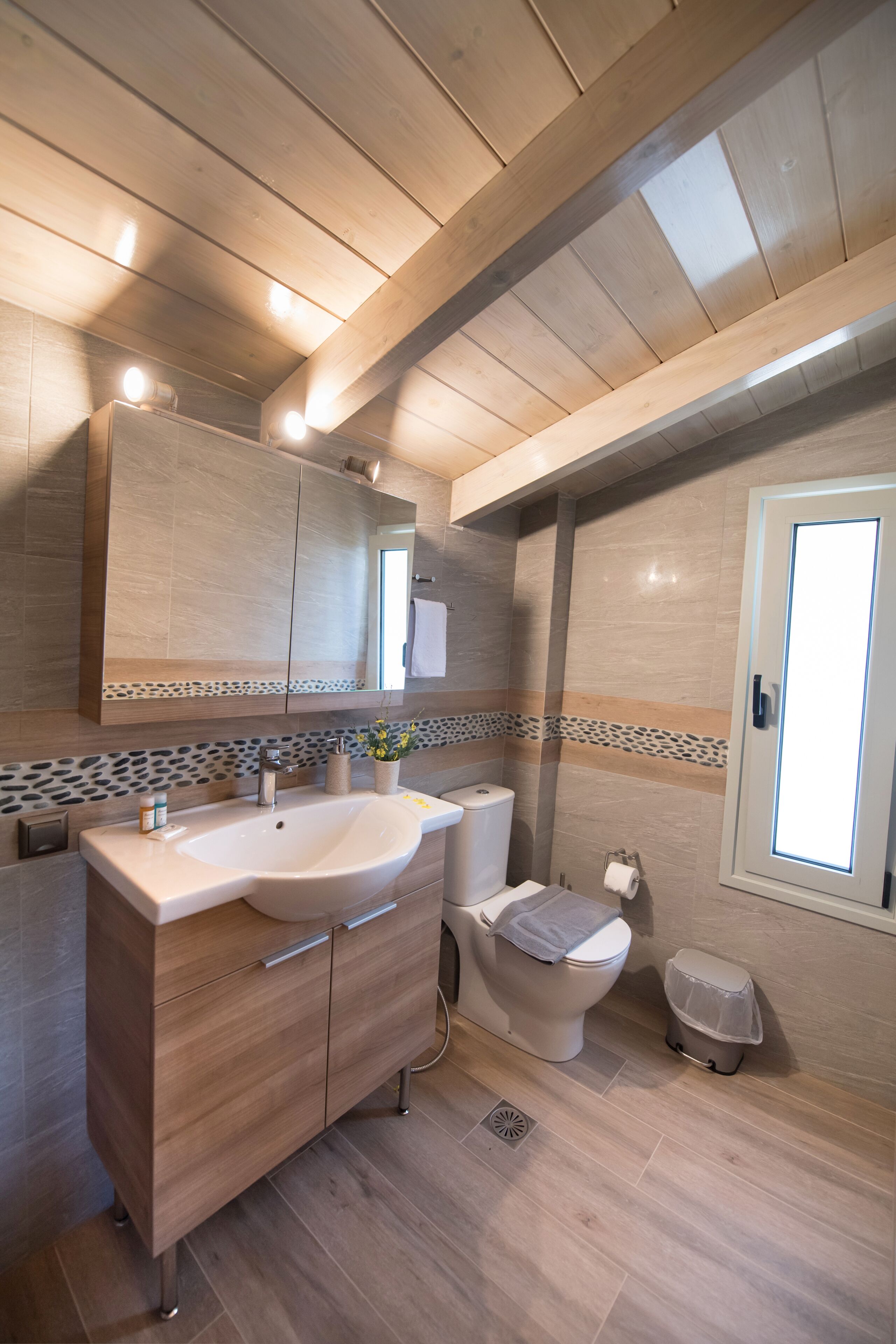 Un baño moderno con tocador de madera, inodoro y zona de ducha.