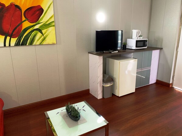 Eine kompakte Küche mit Flachbildfernseher, Mikrowelle und kleinem Kühlschrank.
