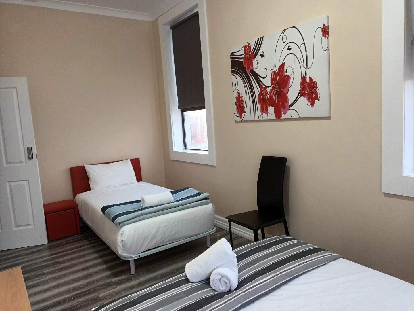 A hotel room with a bed, a chair, a small table, and a window.