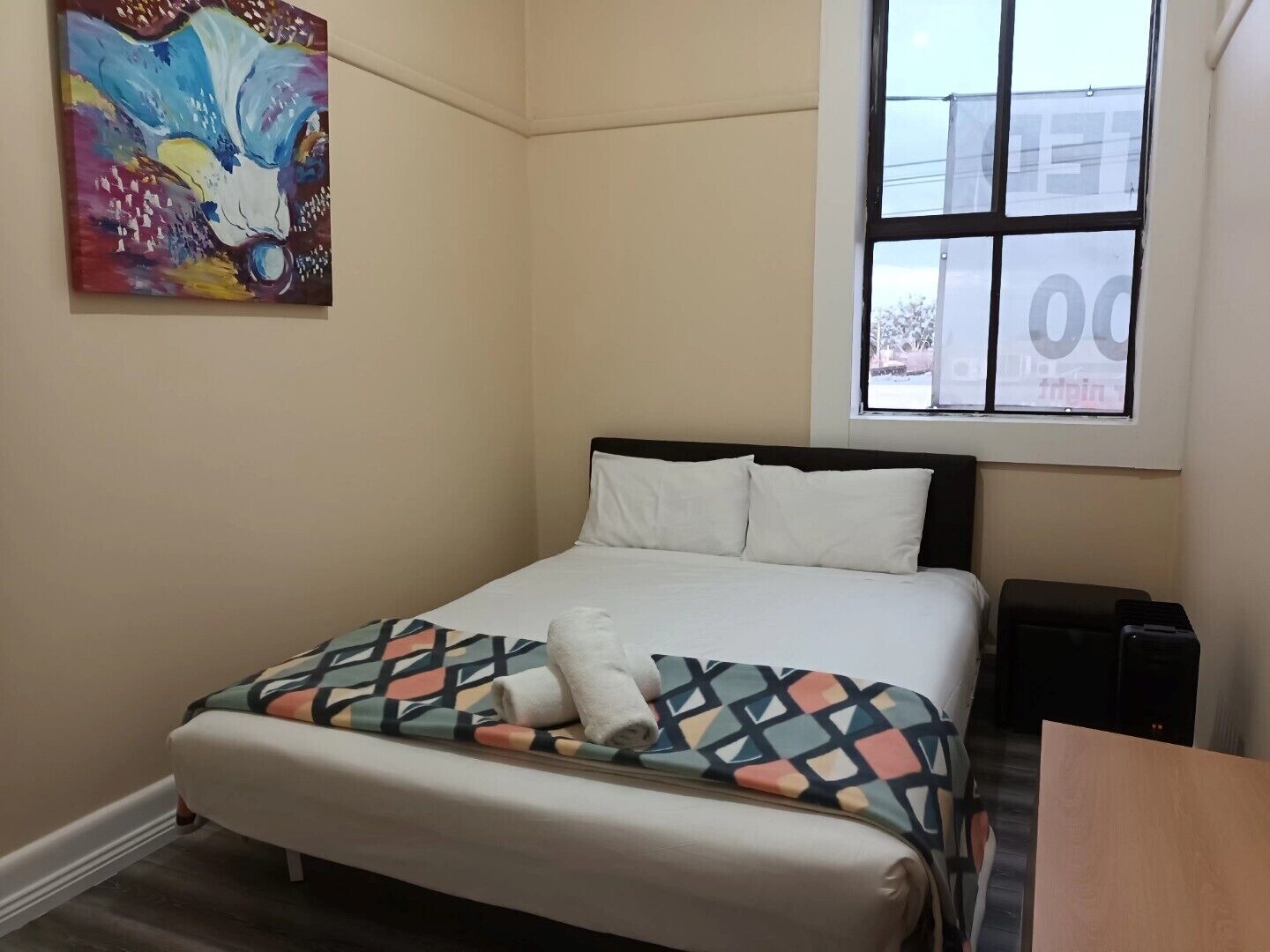Ein Schlafzimmer mit Bett, Fenster, Gemälde und Schreibtisch.