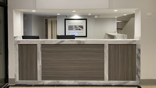 A reception area with a marble counter, framed artwork, and a view of a staircase. - The Hotel Orange (Orange)