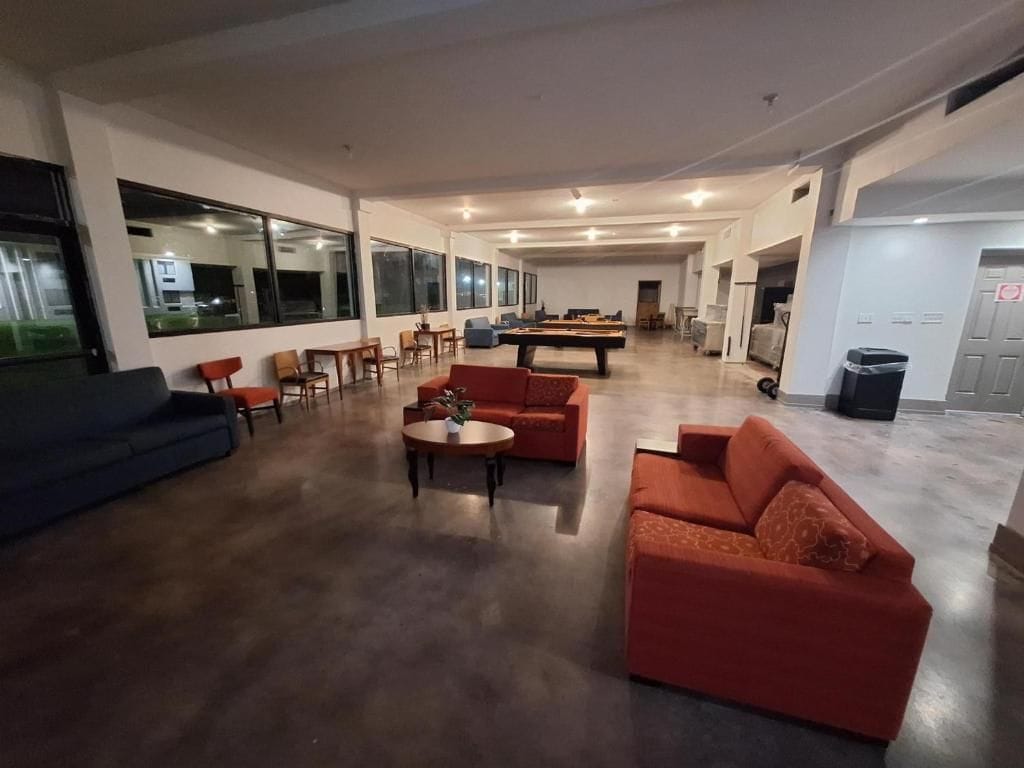 Een ruime woonkamer met een pooltafel, banken en een eethoek.