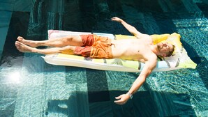 A person lying on a floatation device in a clear pool. - Aurora House (Phu Quoc)