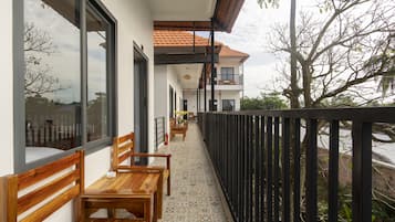A balcony with wooden benches, a tiled floor, and a view of a tree and sky.