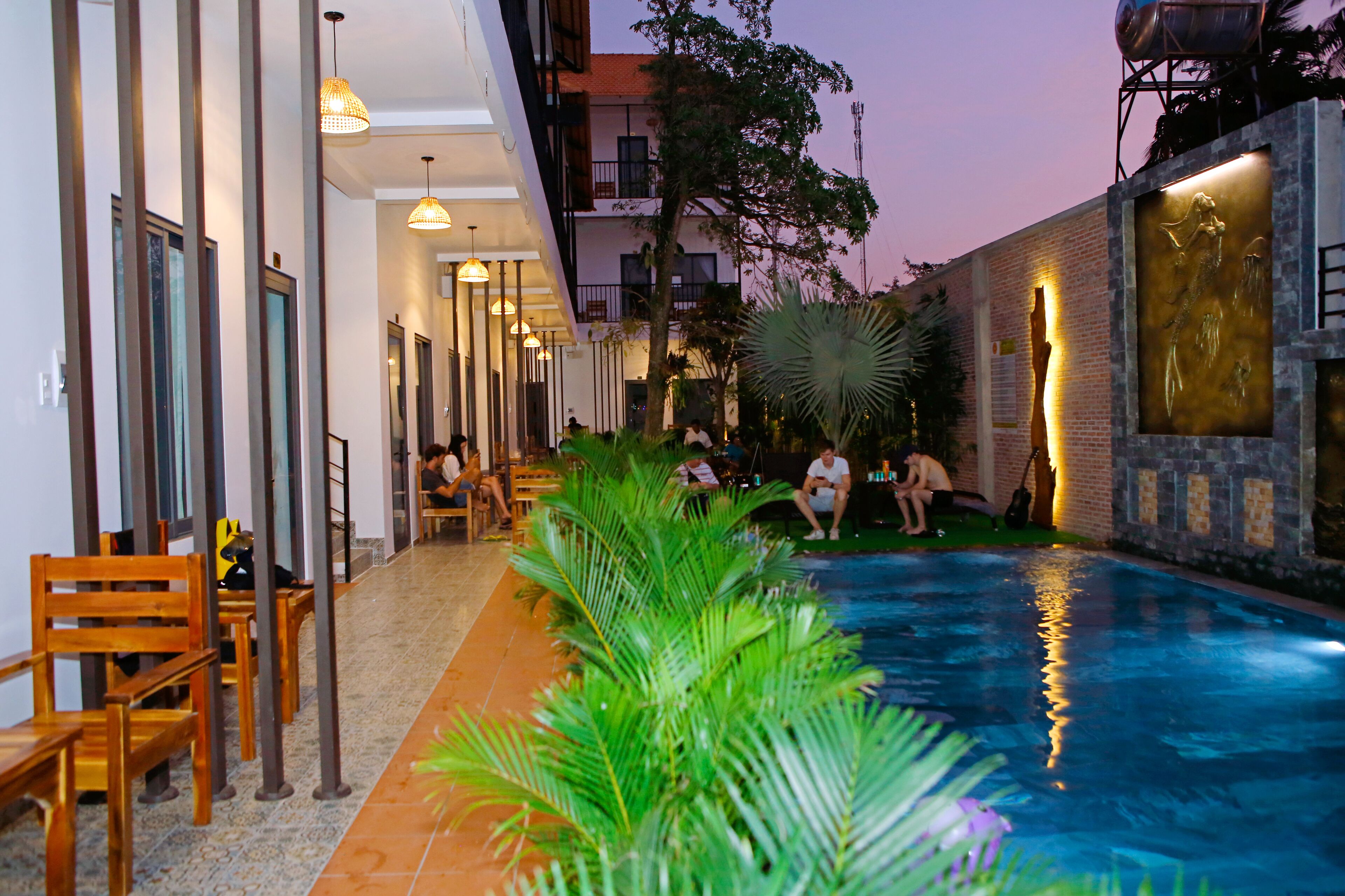 Uma área de piscina com cadeiras e mesas, rodeada por edifícios e vegetação.