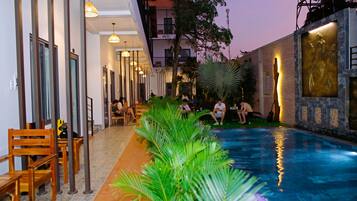 Uma área de piscina com cadeiras e mesas, rodeada por edifícios e vegetação.