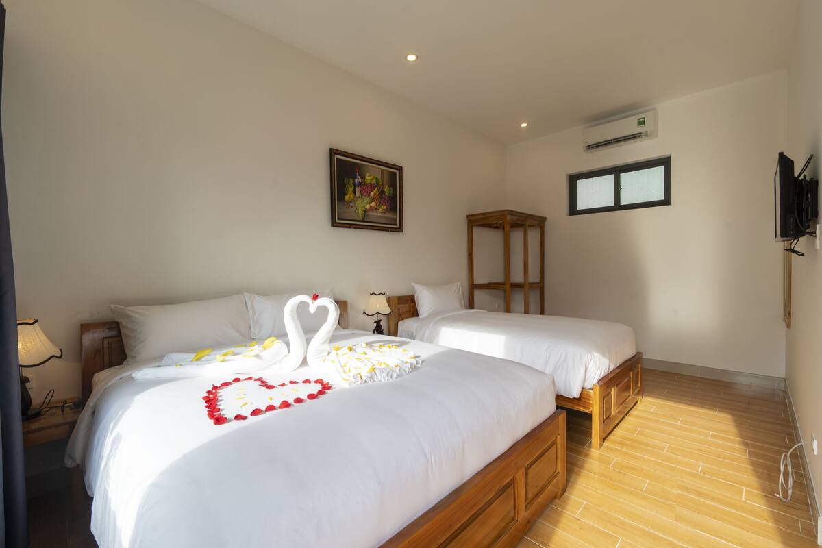 Une chambre d’hôtel avec deux lits, un plancher en bois, un tableau au mur et un appareil de climatisation.