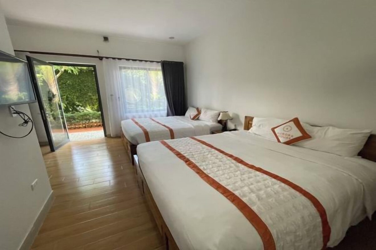 Habitación de hotel con dos camas, televisión y puerta corrediza de vidrio que da a un balcón.