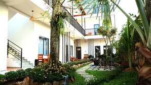 A courtyard with a staircase, outdoor seating, and a variety of plants. - Aurora House (Phu Quoc)