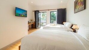 A hotel room with two beds, a desk, a chair, a TV, and a balcony with curtains. - Aurora House (Phu Quoc)