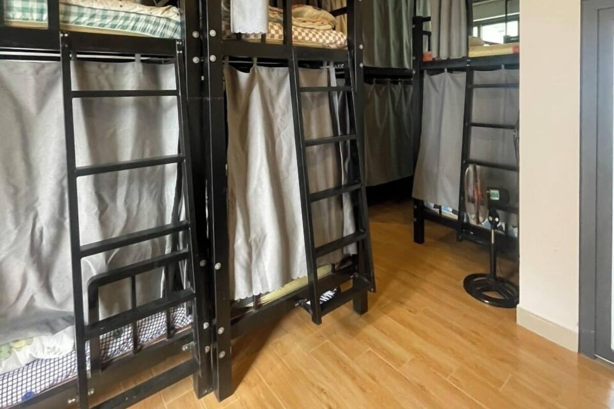 Une chambre avec des lits superposés, un plancher en bois et une petite table avec une chaise.