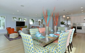 A modern dining area with patterned chairs, a central table with blue and white plates, and decorative branches. - On the Beach: Breathtaking 180 degree views of Gulf of Mexico (Holmes Beach)