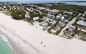 An aerial view of a coastal residential area with houses, a beach, and a marina. - On the Beach: Breathtaking 180 degree views of Gulf of Mexico (Holmes Beach)