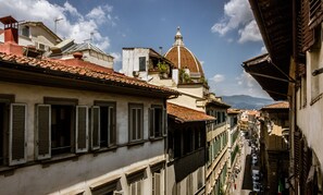 Une rue étroite bordée de bâtiments historiques, dont un bâtiment surmonté d’un dôme et d’un clocher.