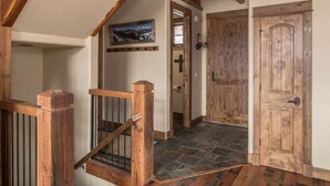 Eine Holztreppe mit Metallgeländer, die zu einem Raum mit Steinboden führt.