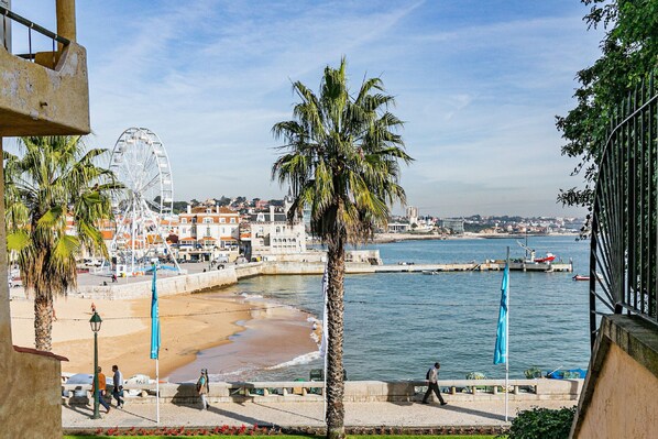 Un paysage urbain côtier avec une plage, des palmiers et une grande roue.