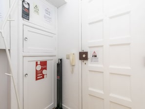 A white door with a security lock, a warning sign, and a notice about a complaints book.